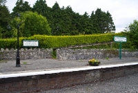 Another view of the disused down platform. Behind the wall the platform could be accessed via a ramp from the adjacent road bridge, note the large notice for passengers wishing to cross the railway line.