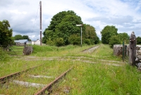 This is the western approach to Castletown, the station being just obscured by the trees and shrubs in the distance. The &#39;Up&#39; distant signal protecting the level crossing also remains in situ here. In the foreground is the gated Killians level crossing, which gives access to a local farm.
