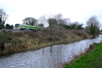 Viewed from the Royal Canal, a 29000 Class railcar passes the site of Clonsilla Junction with a service from Maynooth. The bufferstop at the end of the turnback siding can be seen on the Navan line.