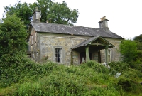 The unsual stone built station building at Crossdonet, showing the porch canopy on the railway side of the structure. The edge of the overgrown down platform can just be seen.