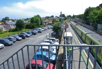 A view looking south from the public side of the footbridge at Dalkey which does not provide access to the station itself. The car park was once the site of the little used goods shed and yard. An 8100 DART awaits departure from the down platform.