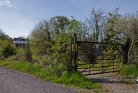 The typical Cork Bandon &#38; South Coast Railway style gate at the entrance to the former goods yard at Desert Station, which can be seen in the background.