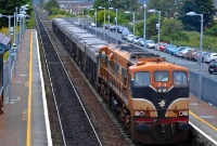Sister locomotive No.074 in faded orange livery leads a southbound rake of loaded ore wagons through Donabate Station. The car park visible behind the up platform was once the site of a siding serving a small goods shed, now llong since demolished.