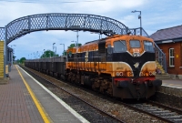 076 passes beneath the cast iron footbridge at Donabate as it heads a loaded southbound Tara Mines train. The ore from the mines is unloaded at the Alexandra Rd in Dublin Port. Donabate originally never had a footbridge; the one seen here is of Great Southern &#38; Western origin and was installed by CIE in 1980.
