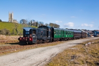 With Down Catherdral overlooking the railway, E Class locomotive No.E421 heads away from Downpatrick with a service to Inch Abbey. The ex CIE green liveried carriage is a former suburban composite carriage built at Inchicore in 1954.