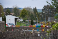 A distant view of the station from Drimoleague level crossing, looking east towards Cork. In the distance was once the road overbridge. The stone wall visible on the left is the abutment of the bridge which carried the Baltimore line across the small River Ruagagh.