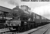 Great Northern Railway&#39;s V Class compound 4-4-0 No.85 &#39;Merlin&#39; stands at Dundalk Station with a southbound Belfast to Dublin train in 1957. Behind the loco can be seen two water tanks, of which only one remains in situ today. ©Wilson Adams Collection