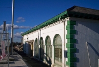 This is the station building as it was in 2003 following the initial completion of the Luas line, the new down platform of which is in the foreground. This view shows the original architectural arches and columns on the railway side of the structure.