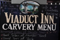 Adjacent to the Chetwynd Viaduct on the N25 road is the &#39;Viaduct In&#39;. The carvery menu depicts a CBSCR tank loco crossing the structure in the mid 1950s. Also in this depiction is the aforemented small garage.